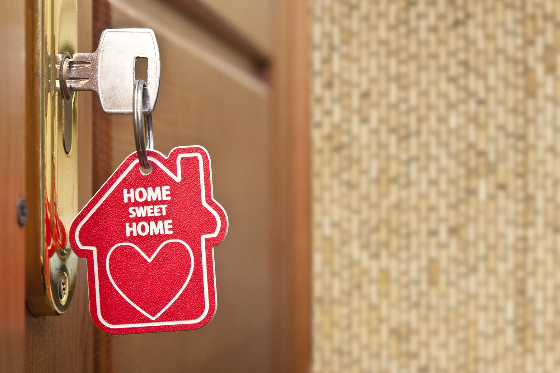 key in a door lock with a "home sweet home" keychain