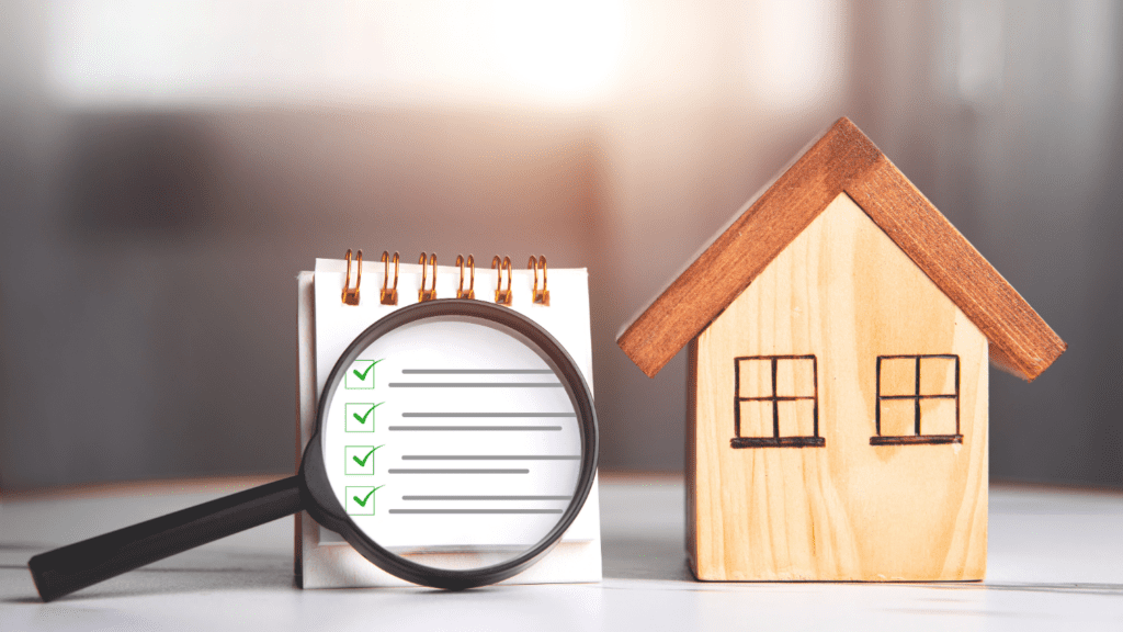 Image of small house replica next to a small note pad and magnification glass over a checklist, representing the home safety checklist.