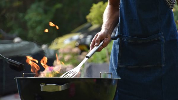 man with apron grilling on a charcoal grill