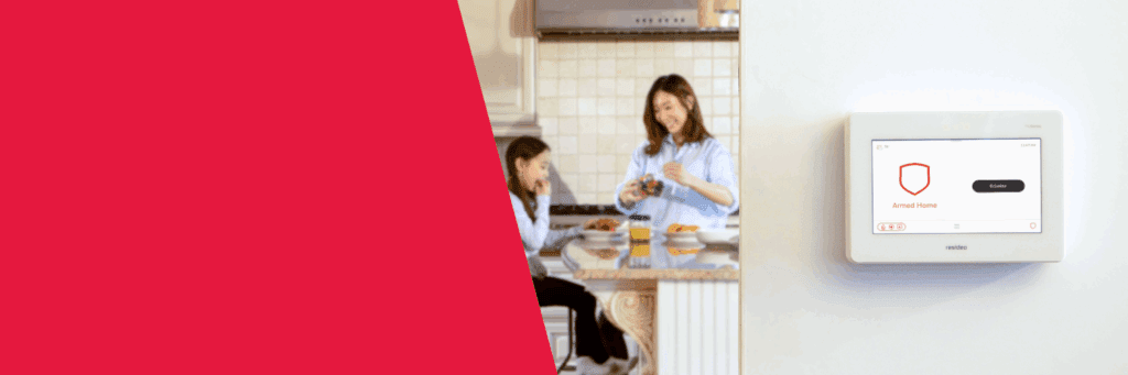 Banner that is half red and half an image of the ProSeries security panel in the foreground mounted on a wall, reading "armed home", and in the background a young girl and her mother in the kitchen talking.