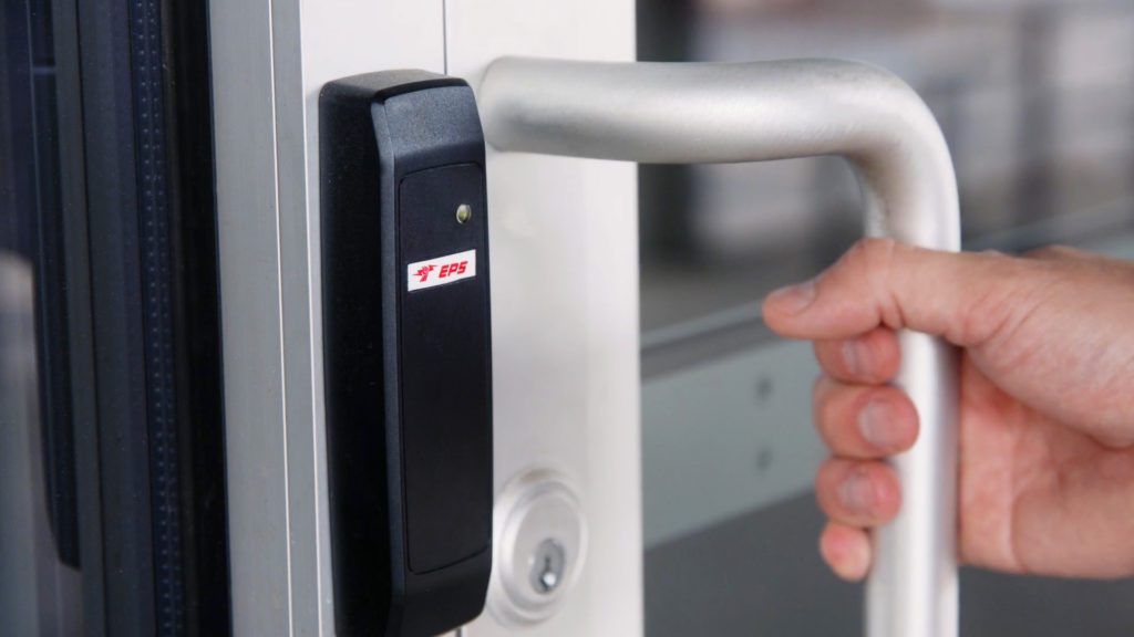 EPS Security access control card reader on business door, hand pulling door open. 
