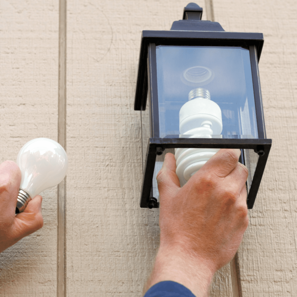 Man's hands replacing exterior lightbulb with a new one