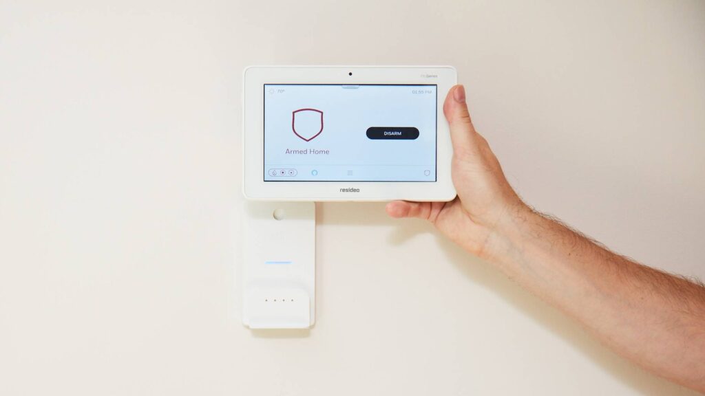 Resideo ProSeries panel being held in front of the wall mount.