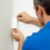 Technician installing a motion detector in a home.