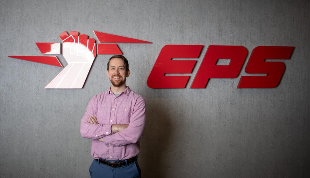 Tony standing with his arms crossed, smiling in front of the EPS Security sign.